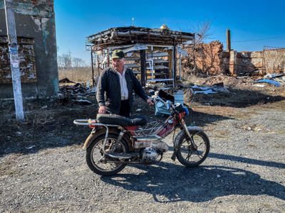 Viktor, a resident of Hrakove village in Kharkiv, stands with his motorbike with scaffolding behind him