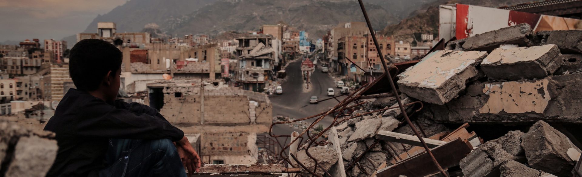 Young boy looks across the ruins of a Yemeni city