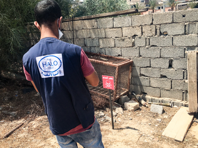 A HALO staff member stands in front of a mine warning sign