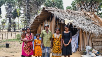 A family stands in front of their home.