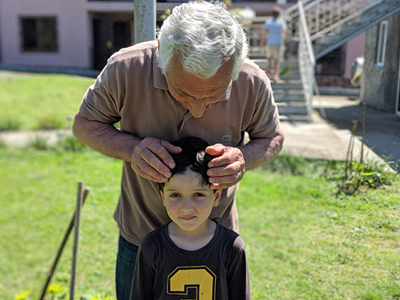 A man with his grandson outside a house in Abkhazia