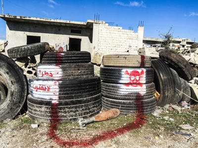 Spray-painted tyres and markings surrounding an unexploded rocket near a home in Syria