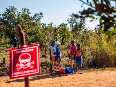 Four children stand on a road behind a danger mine sign in Angola