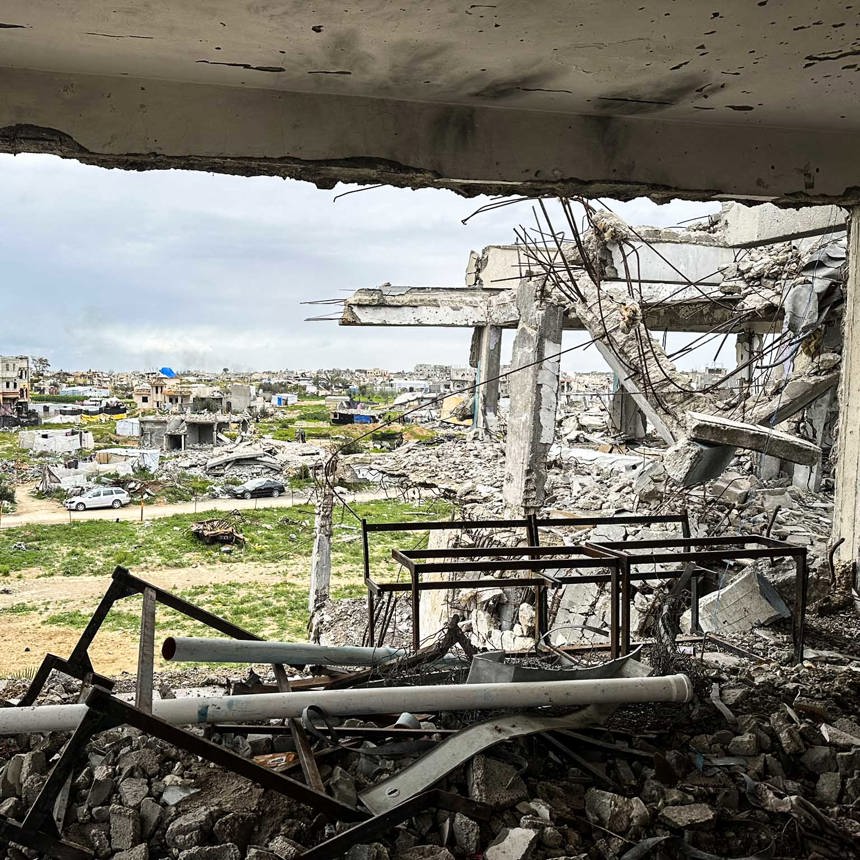 From the opening of a destroyed building, rubble is seen littering the Gaza Strip land