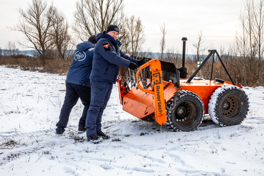 Two HALO staff stand next to a mechanical asset at a training ground in Kyiv region