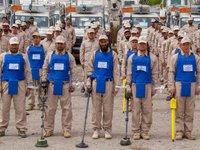 Afghanistan deminers stand in front of their vehicles in ordered rows