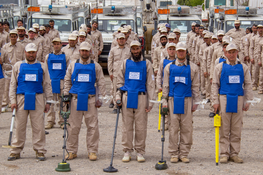 Afghanistan deminers stand in front of their vehicles in ordered rows