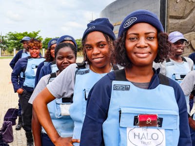 A group of female deminers stand in a line wearing HALO PPE and hats 