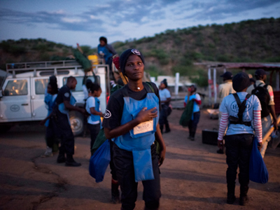 Women wearing PPE carry their bags in preparation