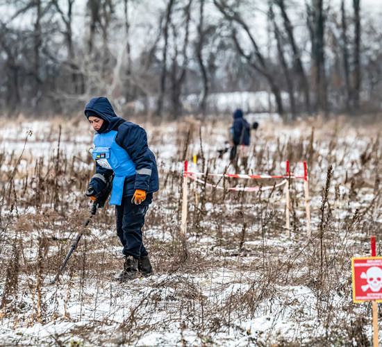 Deminer, Yulia Melnyk, wears blue PPE in a minefield in Ukraine