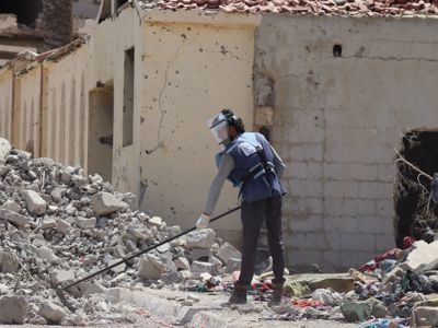 A HALO staff member wearing PPE and clearing rubble in an urban setting