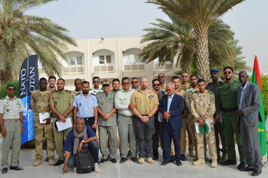 Mauritanian authorities pose as a group in front of NATO flags