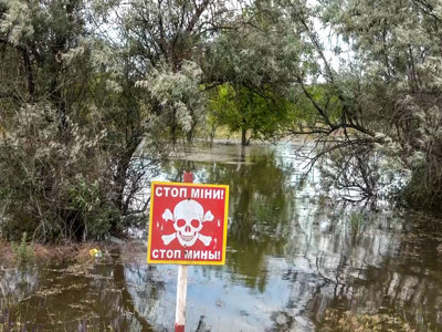 A red danger mines sign stands in front of the destruction of the Kakhovka Dam Flood