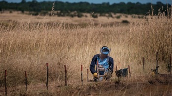 Man in a HALO visor and vest clearing mines in a field in Angola