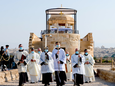 A procession of religious leaders walking through the epiphany site wearing face masks 
