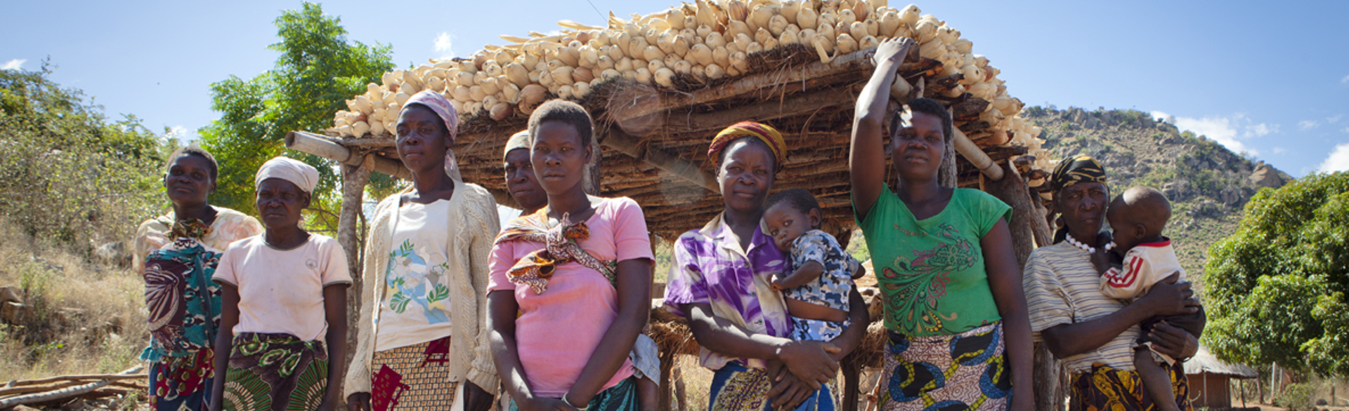 Group of women standing together in front of their maize harvest in Mozambique