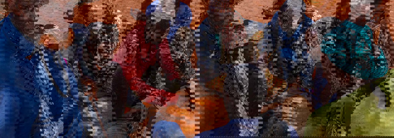 Group of Somaliland men sitting on the orange tinted soil play a game with date stones