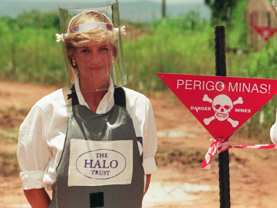 Princess Diana stands in front of a Danger Mines sign in a minefield in Angola
