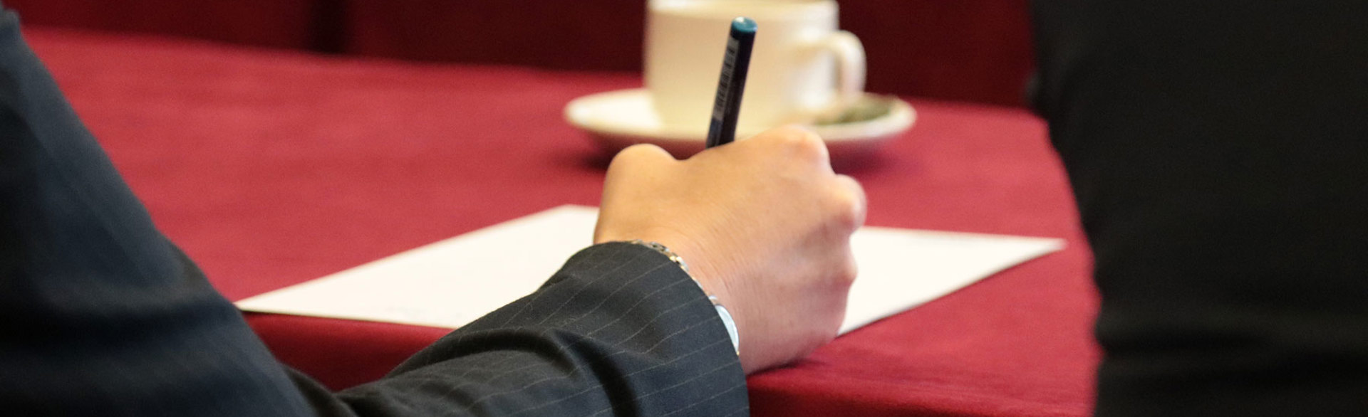 A hand holding a pen to take notes at an event at Chatham House