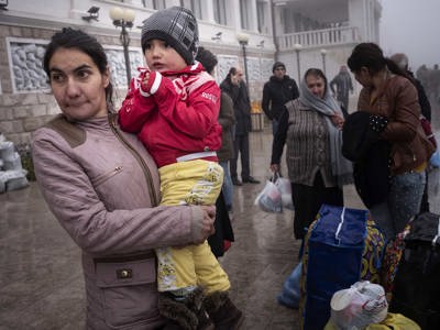 A mother holds her child while standing outside a building