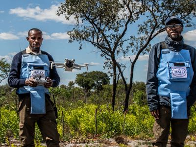 Two HALO Deminers wear PPE while flying a drone in Angola