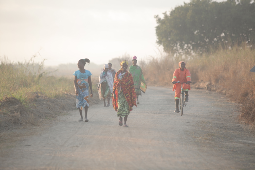 Women in colourful clothes walk along a dirt road in Mozambique