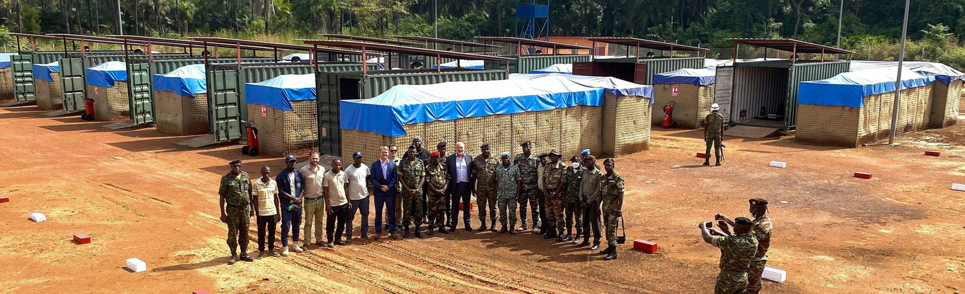 Guinea soldiers and HALO staff pose in front of ammunition storage units outside