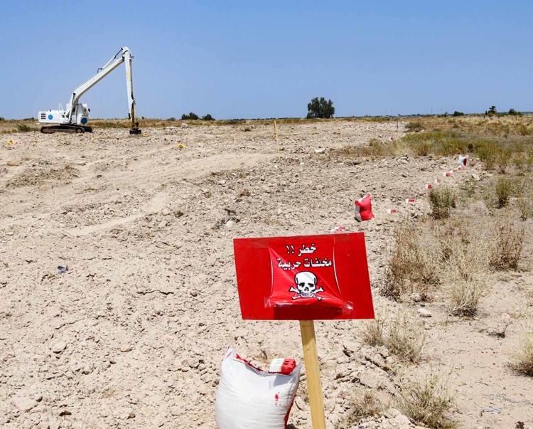 A red mine warning sign stands in front of HALO's mechanical clearance machine